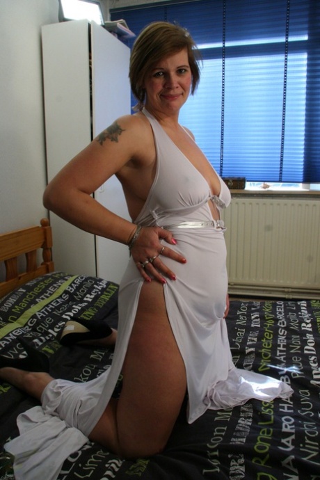 Kinky mature Desiree V lets out her big tits and toys her small pussy on a bed